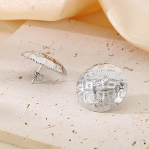 Detailed macro view of silver stud earrings with hammered irregular round metal texture