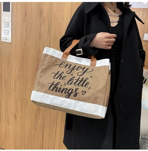 Dettaglio della borsa tote in lino con stampa artistica e manici in pelle marrone moda