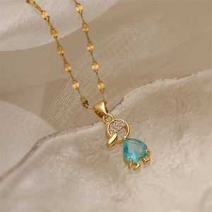 Detail of gold necklace featuring girl pendant with heart blue gem and pavé zircons