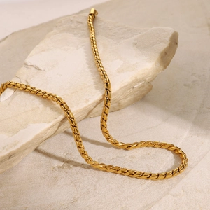 Macro detail of 18K gold plated stainless steel woven chain on natural stone background