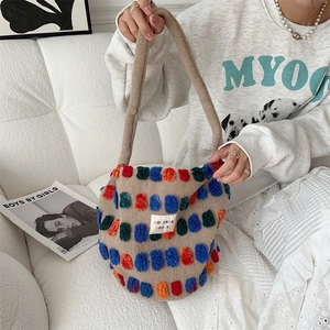 Detail shot of plush khaki bucket bag featuring colorful textured dots and brand label