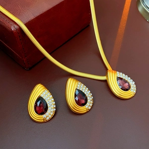 Detail of vintage teardrop earrings and necklace set with red gems and crystals