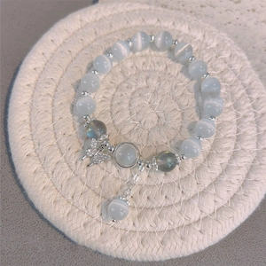 Vue détaillée d'un bracelet de perles avec pendentif papillon et pierres œil-de-chat