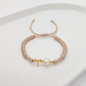 Detail of champagne woven bracelet featuring white pearl and golden letter Y charm