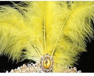 Detail of yellow mask with vibrant feathers, golden gemstone, and intricate lace