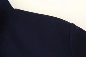 Detaillierte Nahaufnahme der Schulternaht und Kragentextur der marineblauen Wolljacke
