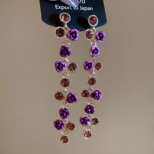 Detailed shot of elegant long tassel earrings with purple resin rose and amber crystals