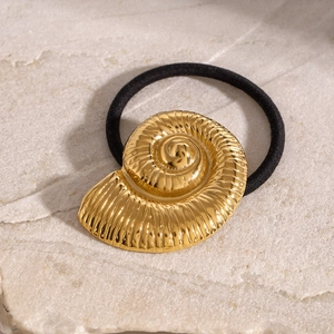Elegant gold ammonite shell hair tie on black elastic band with a stone background