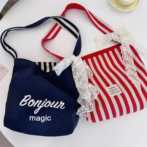 Detailed flat lay of striped canvas tote bags with elegant lace trim and blue bonjour prints
