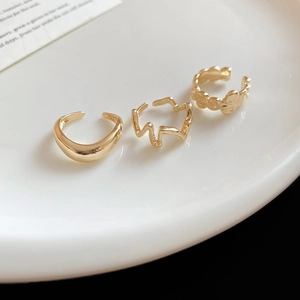 Close-up of three gold geometric rings with S925 hallmark on a white ceramic tray