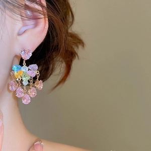 Macro side view of elegant heart and teardrop colorful crystal tassel earrings on model