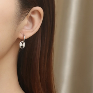 Macro side view of silver pig nose anchor link earrings worn by a woman for style