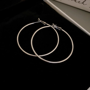 Macro shot of polished silver hoop earrings on a black velvet background with mirror finish