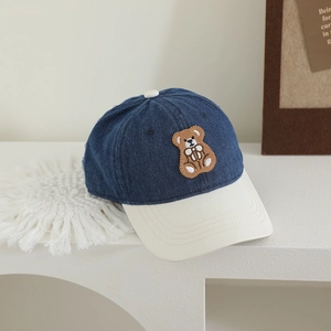 Detailed close-up of brown bear embroidery and denim texture on children's baseball cap