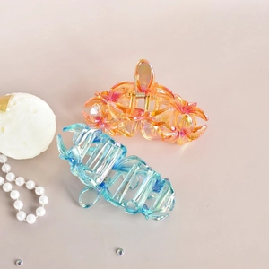 Detail of floral hair clips with gradient colors and iridescent finish on a neutral base