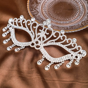 Detail of silver rhinestone mask with hollow patterns and water drop crystals on satin