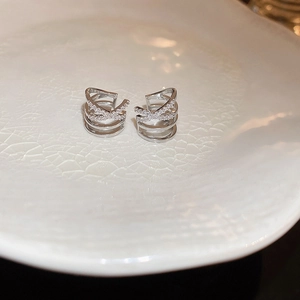 Macro shot of silver multi-layered crisscross ear cuff earrings with sparkling zircon