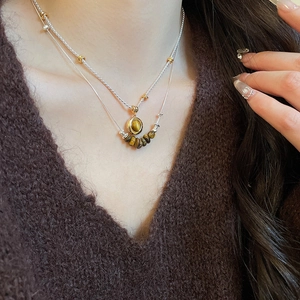 Detail of layered tiger eye stone necklaces on a brown knit sweater showing natural texture