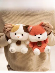 Close-up of plush cat dolls with wooden tags and heart embroidery on paws