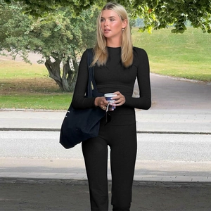 Detail shot of black slim-fit crew neck top and high-waisted flared pants two-piece set