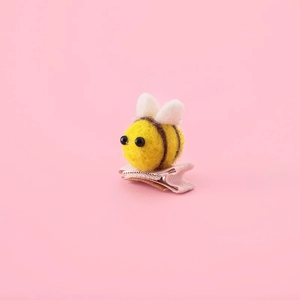 Detail of wool felt bee hair clip showing fiber texture and craftsmanship on pink background
