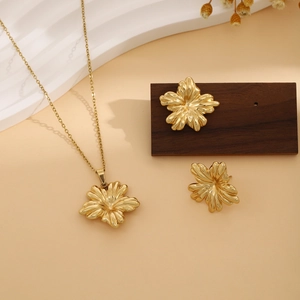 Macro shot of gold floral necklace and earrings set on a decorative wooden display block