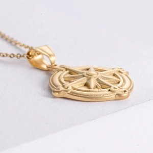 Macro detail of gold plated compass pendant necklace on white textured geometric block