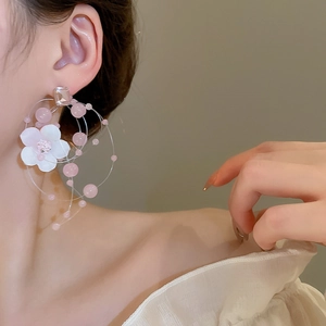 Close-up of pink beaded floral tassel earrings featuring a white fabric flower detail
