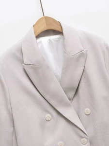 Detailed view of grey double-breasted blazer fabric texture and cream buttons