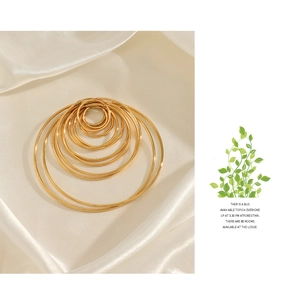 Flat lay of seven pairs of gold hoop earrings in varying sizes on white satin fabric