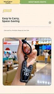 Close-up of black leather rock hand gesture keychain with white stitching and metal ring
