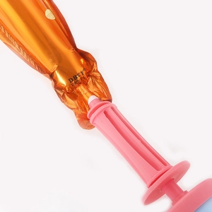 Pompa ad aria manuale rosa che gonfia un palloncino in foil arancione su sfondo bianco
