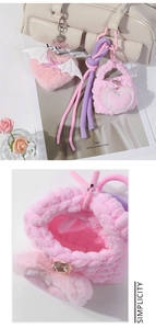 Close-up of pink plush heart charm with white wings and mini woven bag accessory