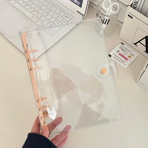 Detail of A6 transparent PVC 6-ring binder with pastel pink clips on an aesthetic desk