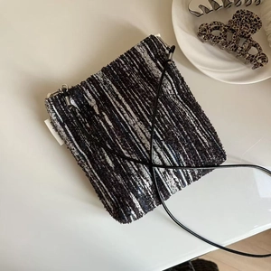 Close-up of black and white tweed mini crossbody bag with a simple wish side label