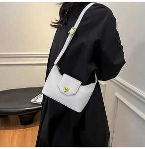 Detail of white glossy underarm bag with gold metal buckle and adjustable shoulder strap