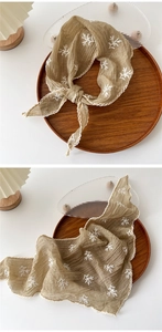Close-up of beige cotton linen scarf with leaf embroidery and white lace edges