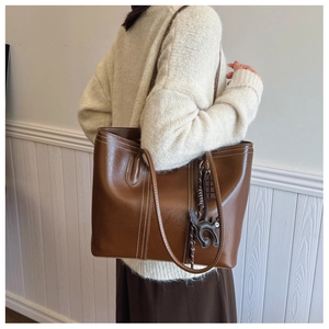 Detail of deep brown tote bag featuring contrast stitching and soft oil-wax leather texture