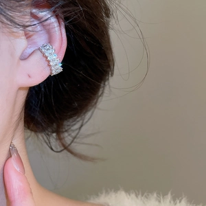 Détail d'un ear cuff argenté avec étoiles en zircon et perles porté sur le cartilage