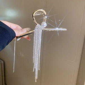 Détail d'une pince à cheveux argentée avec perle blanche et longs glands en strass
