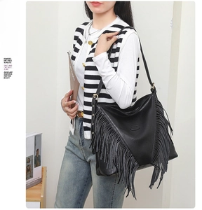 Détail du sac à franges en cuir noir avec bandoulière réglable et détails métalliques dorés
