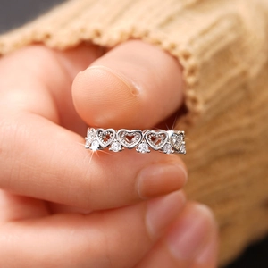 Close-up of silver hollow heart-shaped ring with pavé zircons on a model's finger