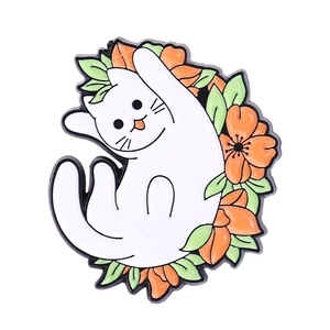 Detail shot of a cartoon white cat enamel pin with orange flowers and green leaves