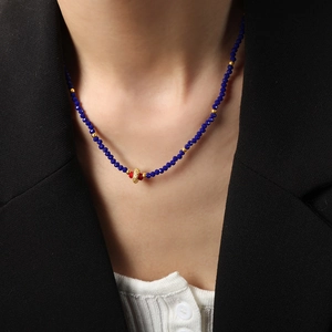 Elegant navy blue faceted bead necklace with gold hollow pendant on a black blazer model