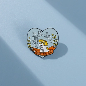 Detail of blue heart enamel pin with cute dog and inspirational quote text engraving