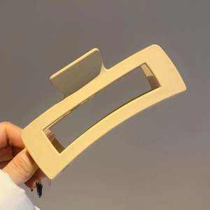 Close-up of a large beige matte resin hair claw clip in a minimalist rectangular design