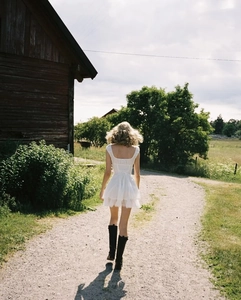 Detail of white backless dress with layered ruffles and lace trim in a rural setting