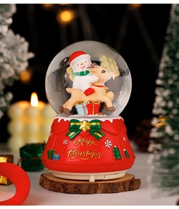 Macro shot of a Christmas crystal ball music box with snowman riding reindeer figurine