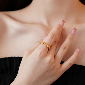 Detailed view of a gold bamboo-style ring with sparkling zircon inlays on a model's finger