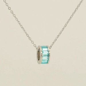 Macro detail of silver stainless steel necklace with light blue crystal ring pendant